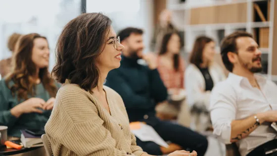 Group of adults at a focus group with woman in glasses half-smiling.