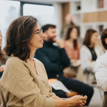 A group of adults sit in an audience of a training event. 